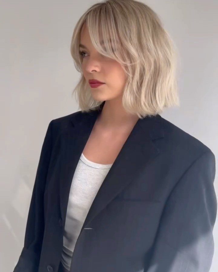 Woman with tousled blonde side bangs bob wearing a dark blazer