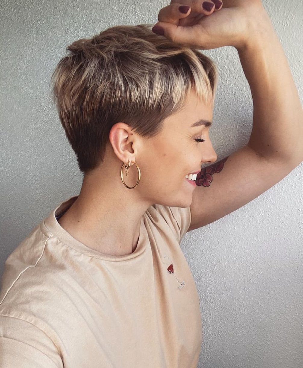 Woman showcasing a textured tapered blonde pixie haircut with closely trimmed sides