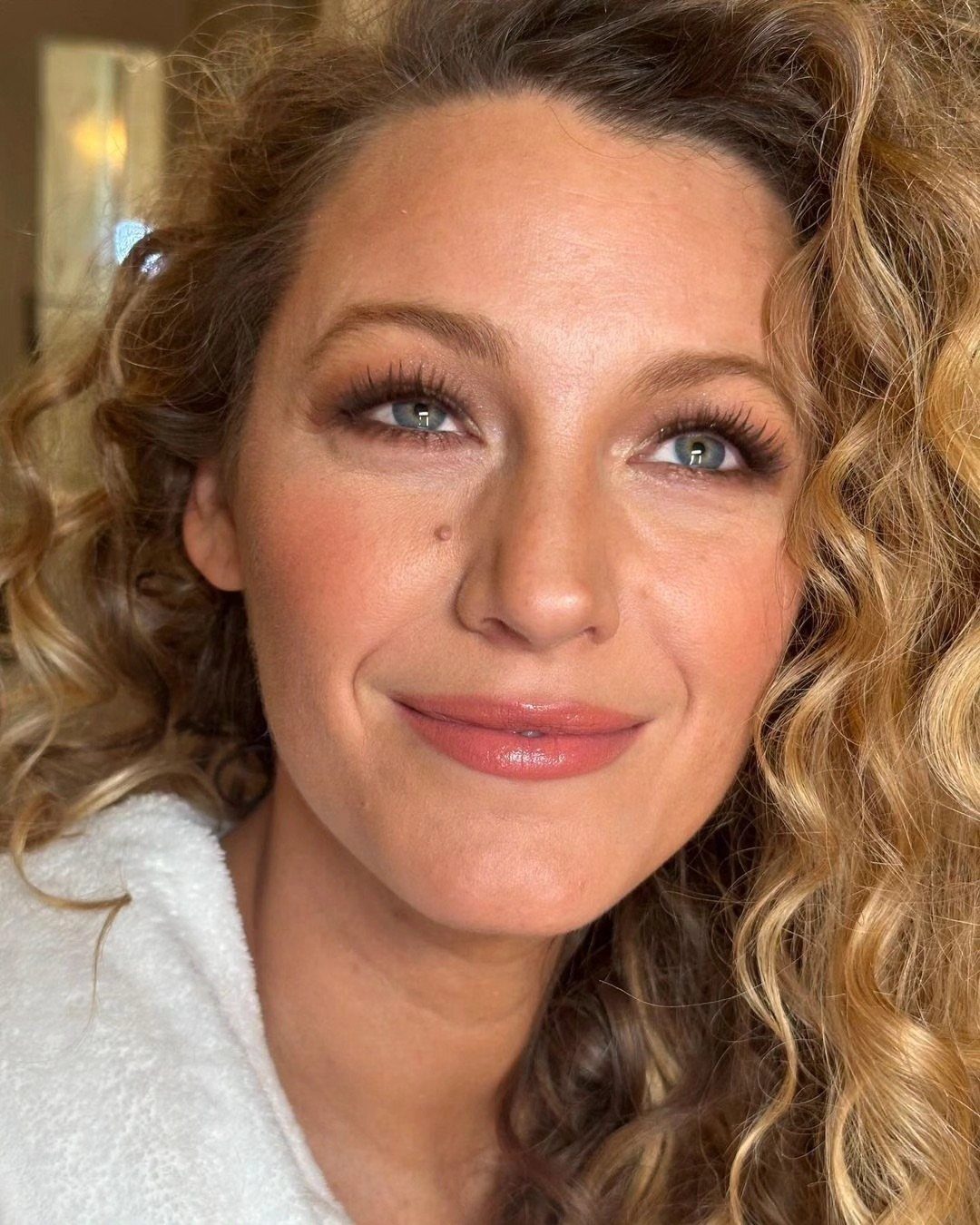 Blake Lively with long, curly strawberry-blonde hair and lighter highlights