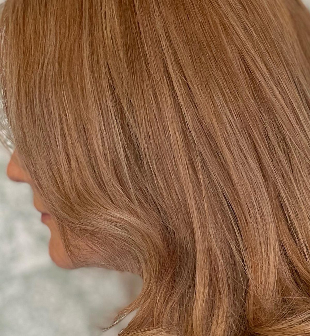 Reddish-blonde layered hair falls smoothly across the side of a person's face