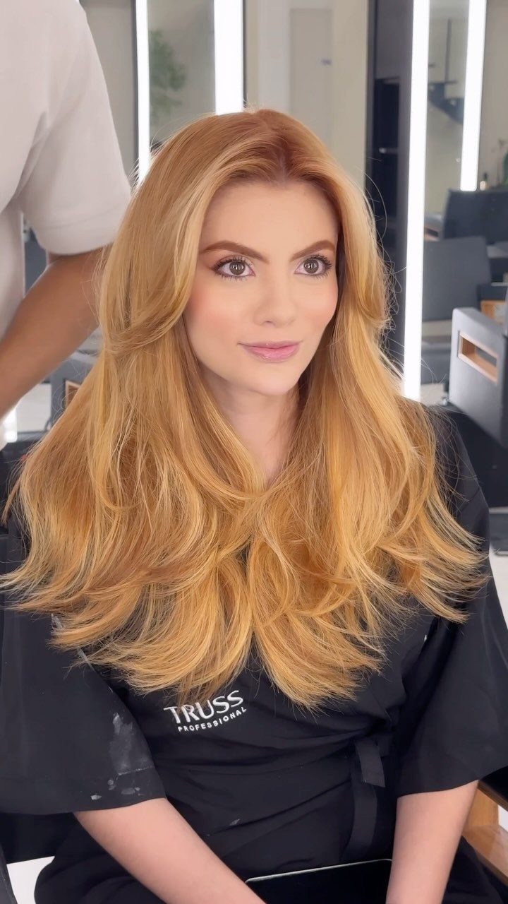 Woman with long, softly waved strawberry blonde hair seated in a salon