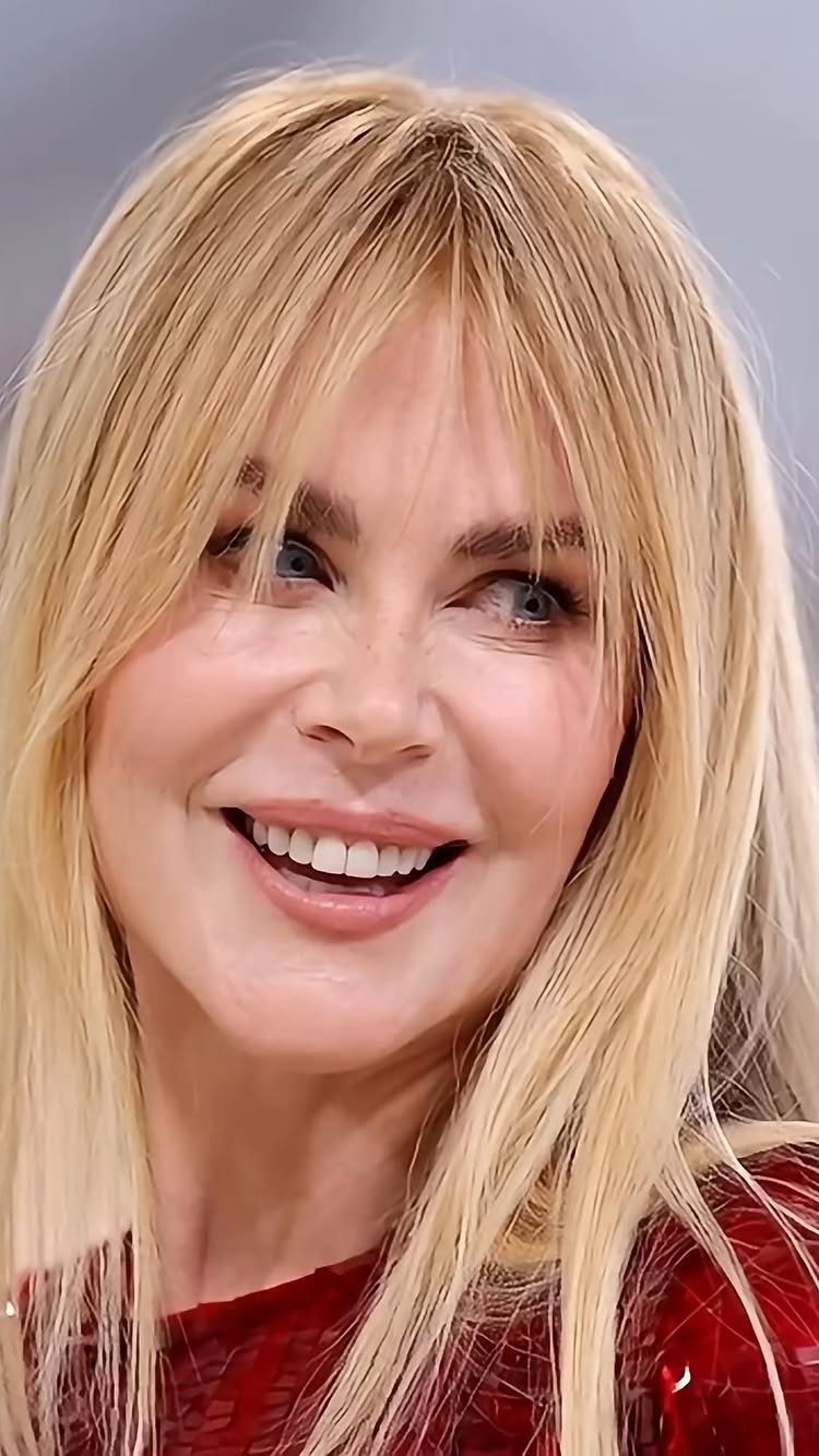 Smiling woman with long, center-parted strawberry-blonde hair and bangs