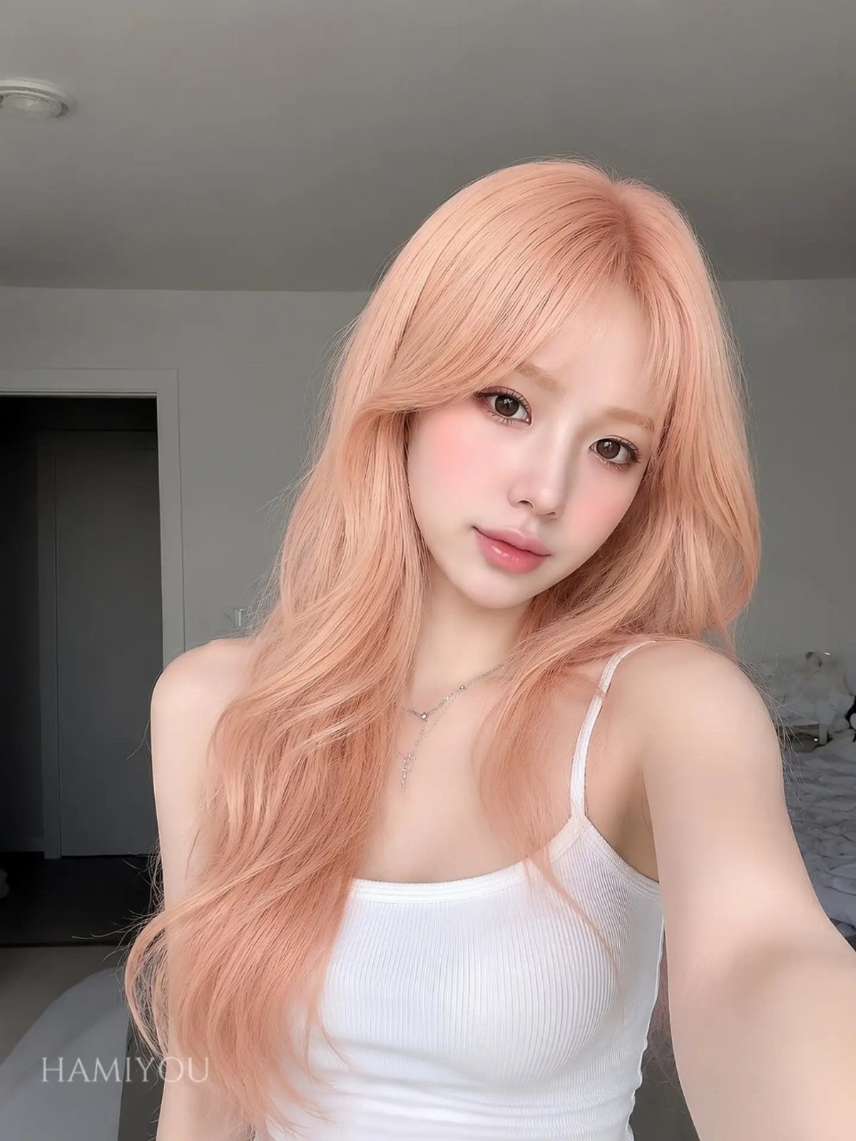 Woman with long peach strawberry blonde waves and bangs in a white tank top