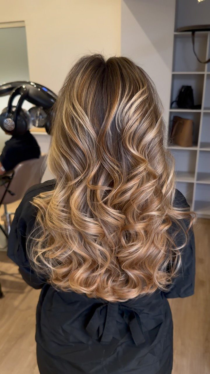 Long wavy blonde balayage with warm golden pieces and darker roots