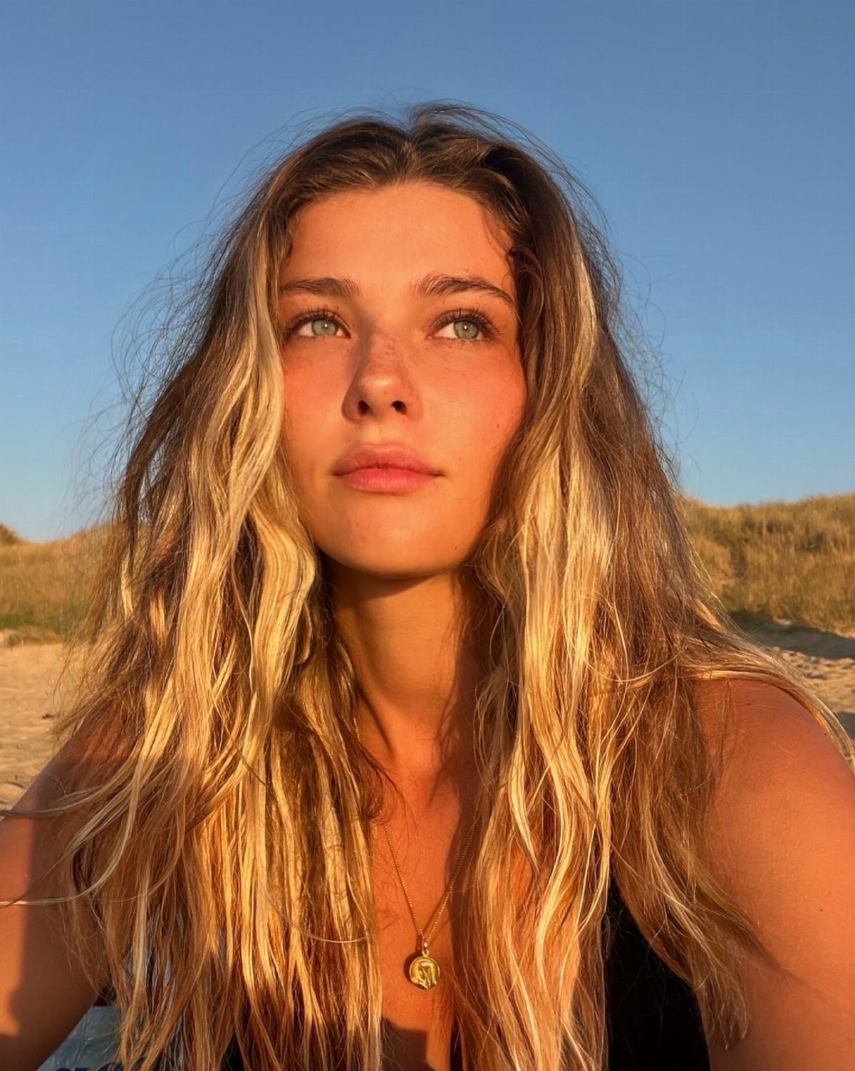 Woman with long warm blonde beach waves and sunlit lighter ends outdoors