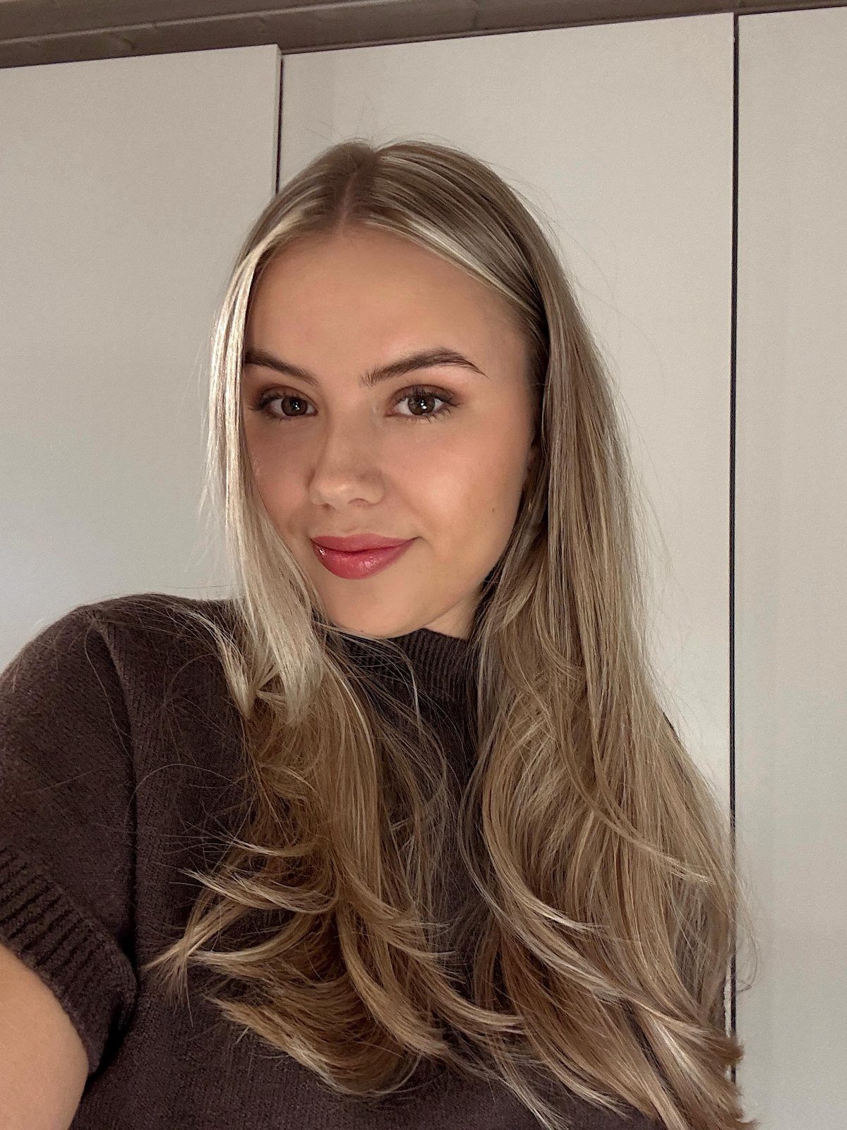 Woman with long warm blonde waves and a rich brown base indoors