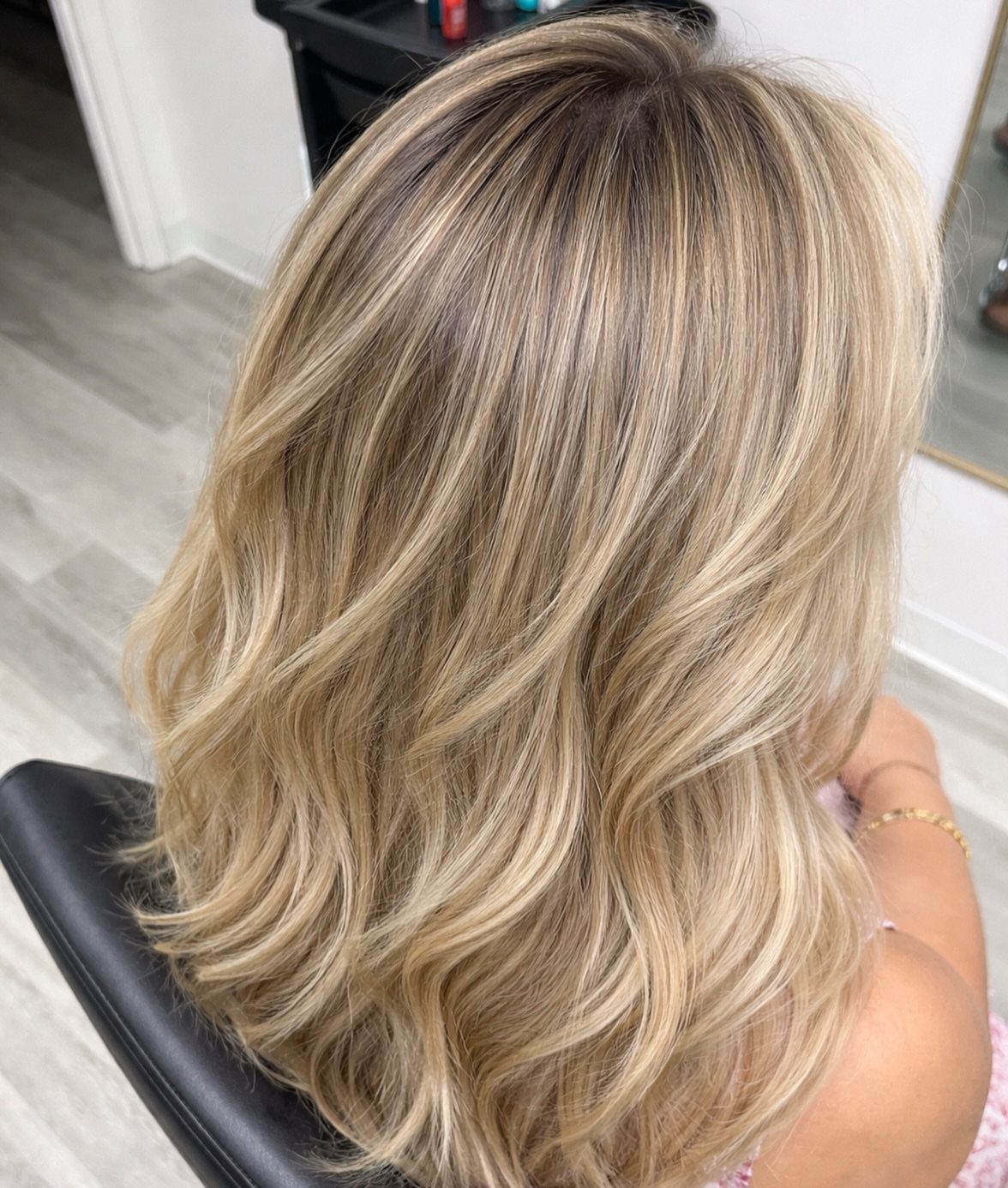 Blonde hair with softly blended darker roots and lighter wavy lengths