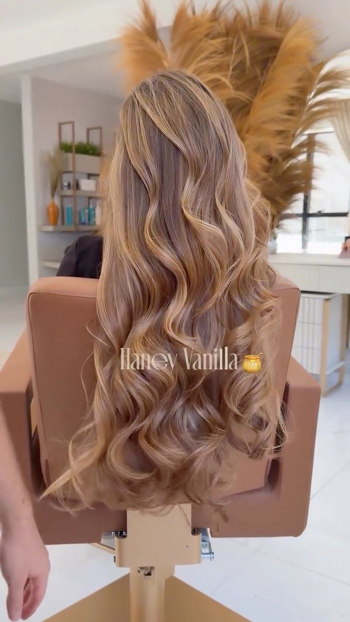 Long warm honey-blonde hair styled in loose curls with darker roots