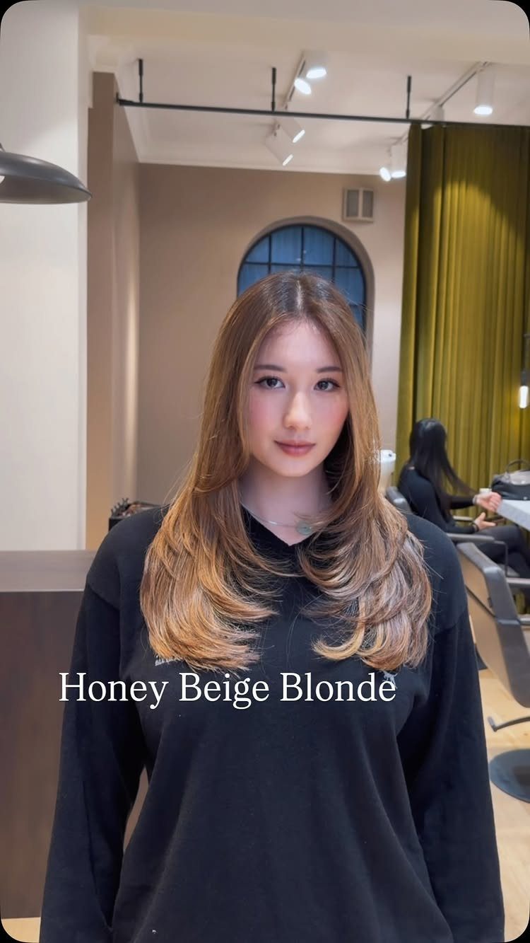 Woman displaying long honey-beige blonde hair with voluminous, curled layers