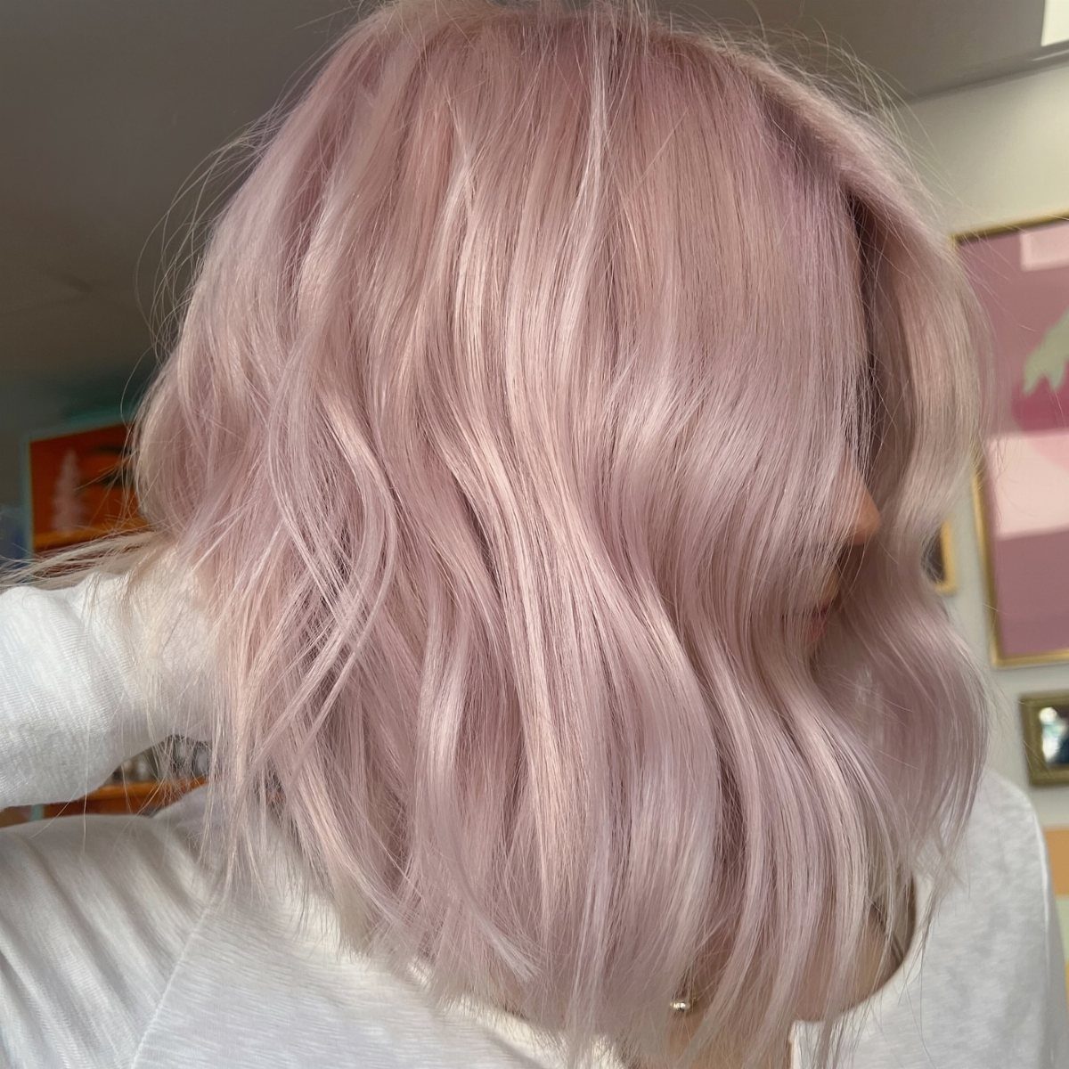 Long blush-pink blonde hair falls in soft waves over a light gray top