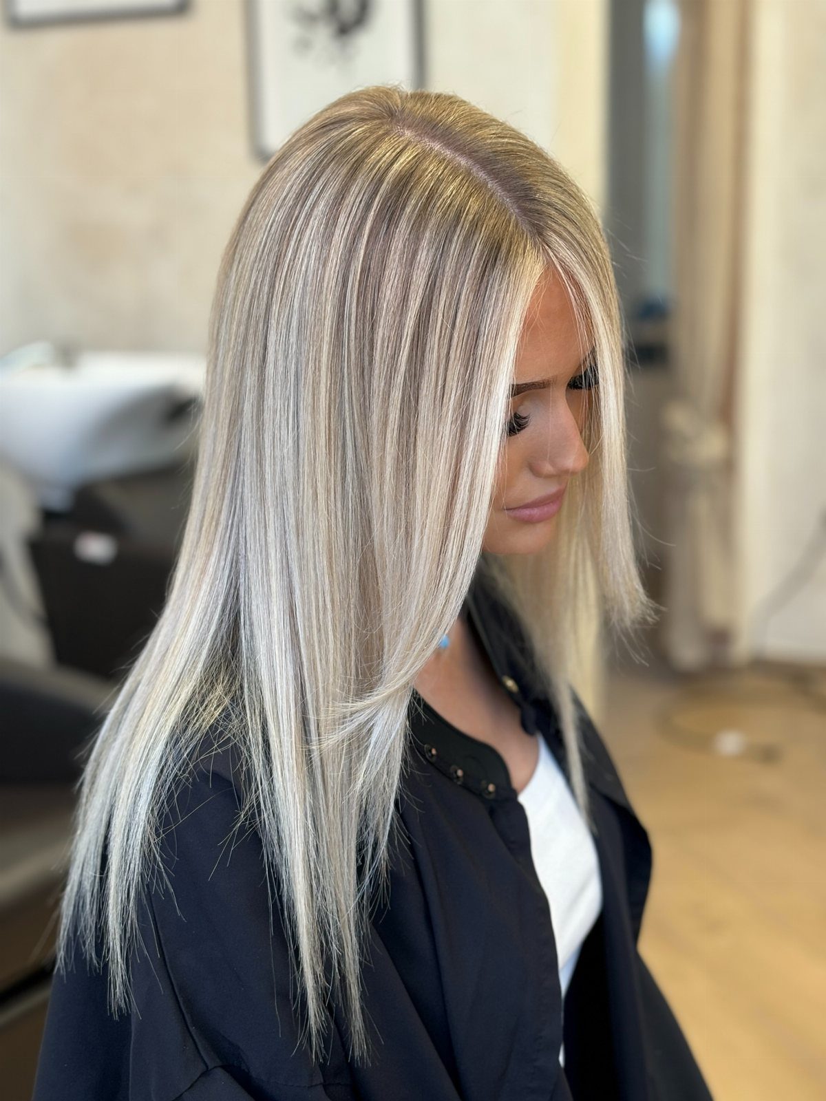 Woman with sleek center-parted platinum hair falling straight past her shoulders