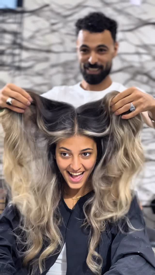 Woman showing long wavy pale blonde hair with dark roots
