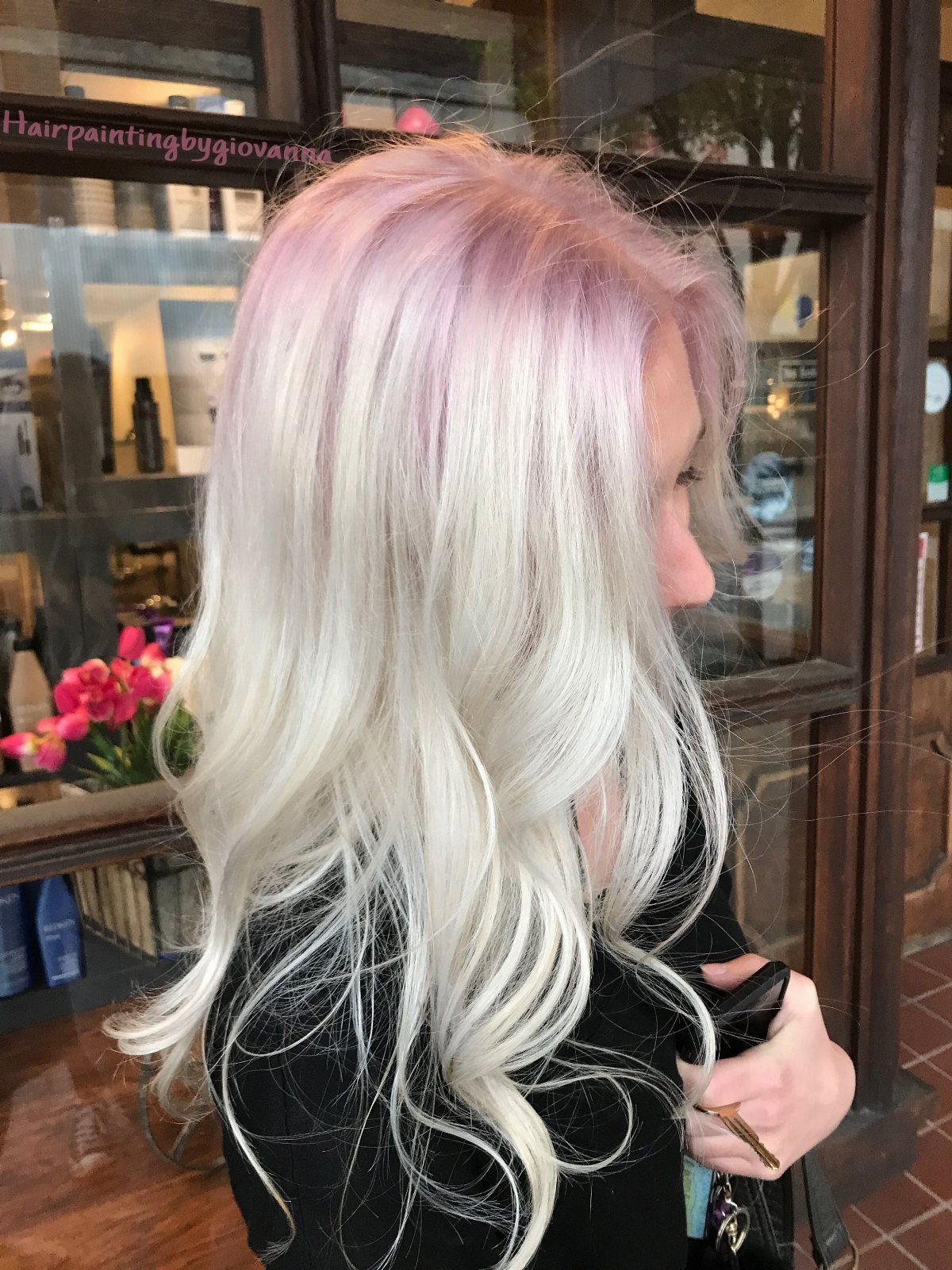Long white-blonde hair with soft pink-peach roots in a salon