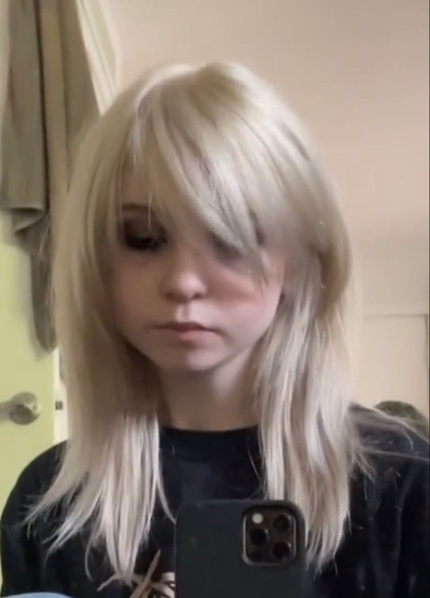 Person with long white-blonde hair and heavy side-swept bangs covering one eye