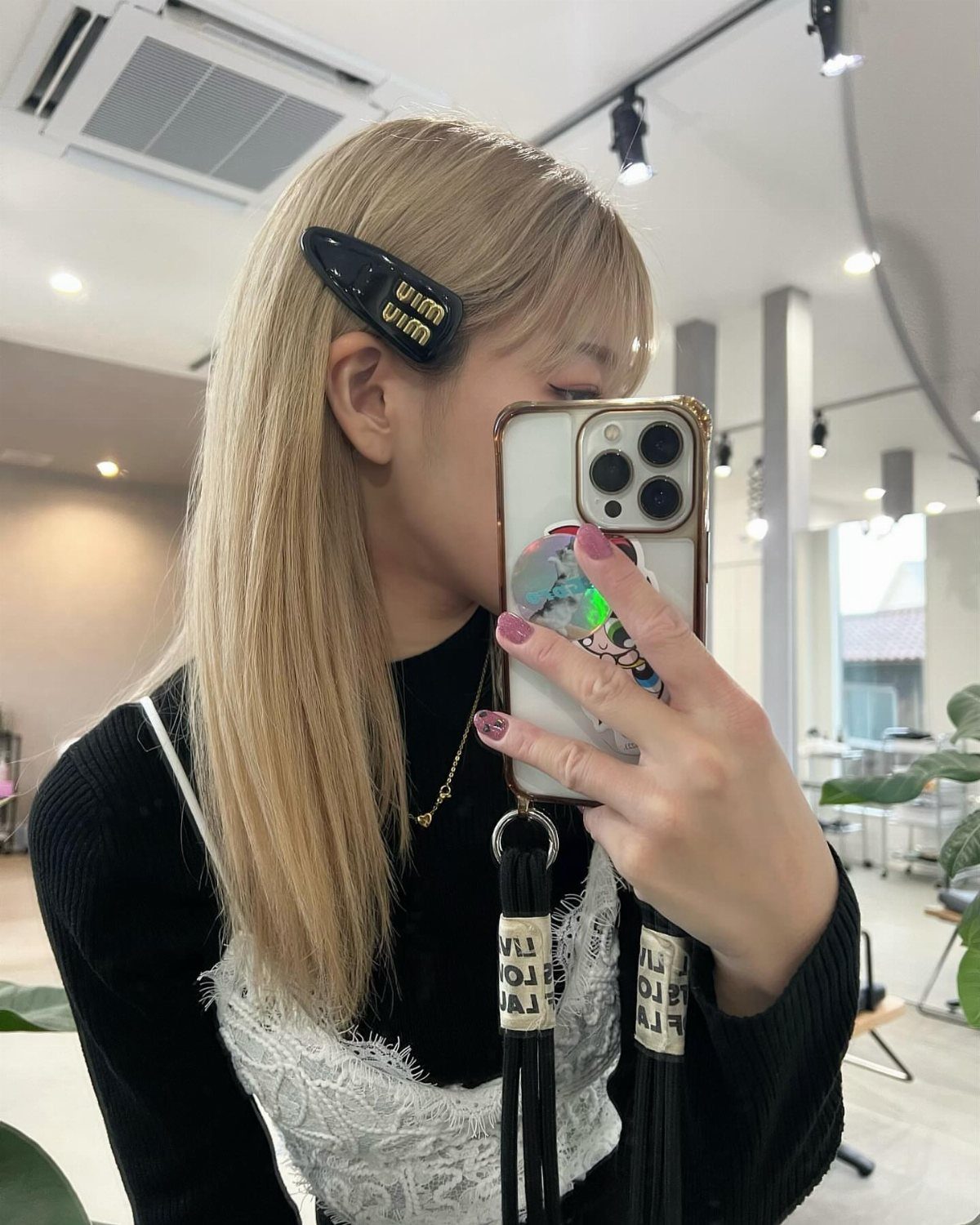 Long straight pale blonde hair pinned back above the ear with a dark barrette