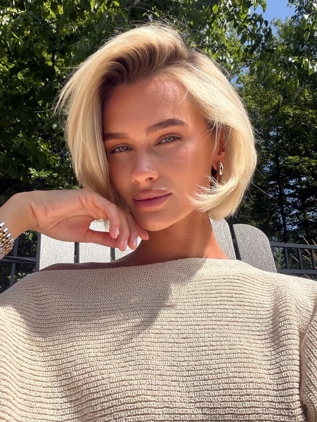 Side-parted pale blonde lob frames a person's face outdoors