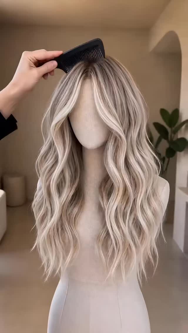 Mannequin with long white-blonde hair in loose waves as a hand holds a comb
